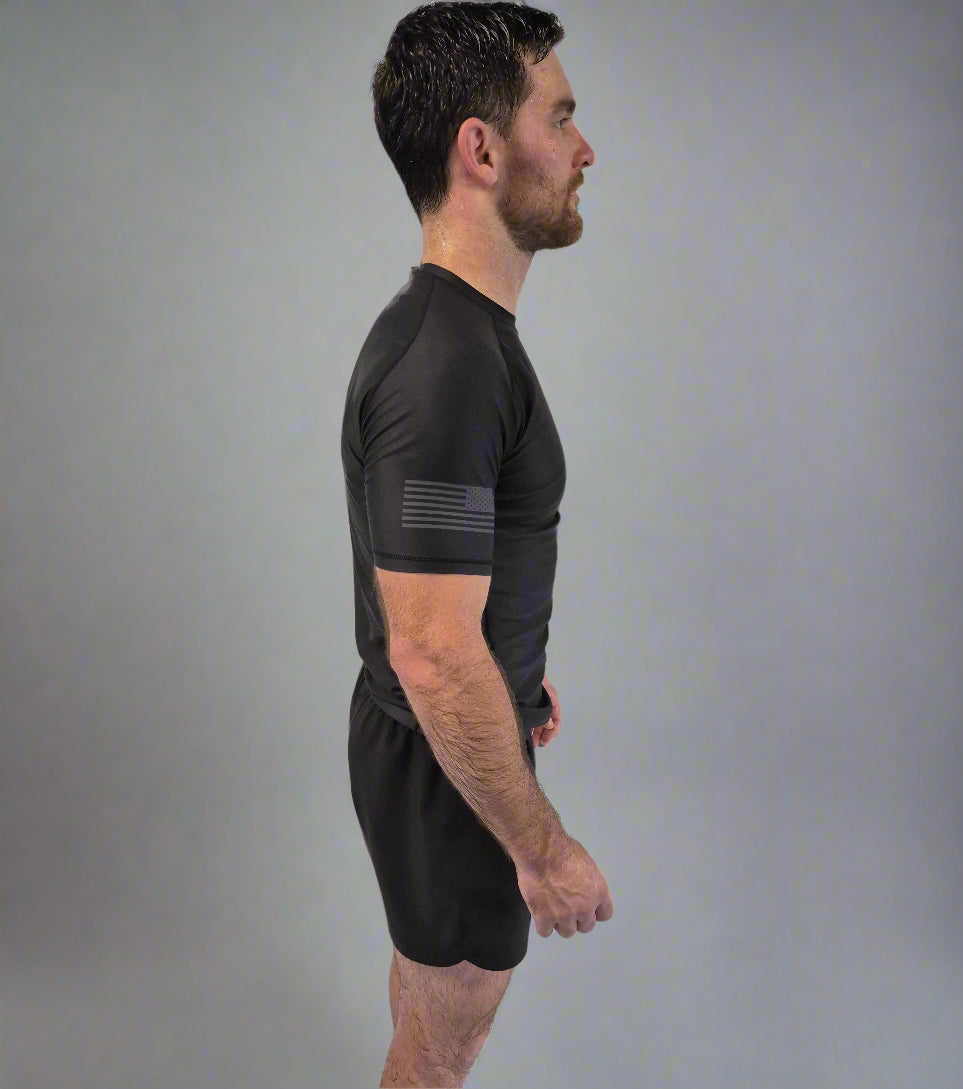 Man wearing a black athletic outfit standing against a white curtain