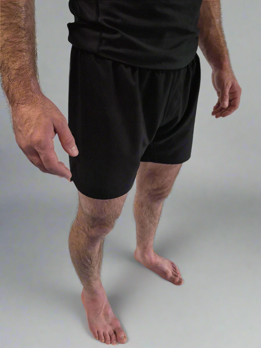 Person wearing black shorts standing on a white background